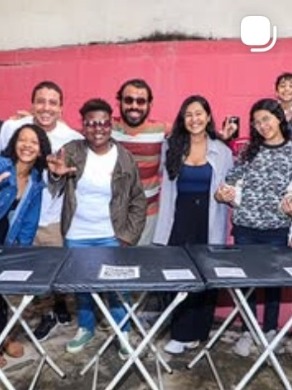 Jovens sorrindo atrás de uma mesa em evento