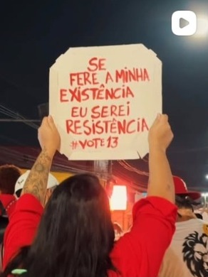 Mão erguendo cartaz escrito: Se fere a minha existência eu serei resistência